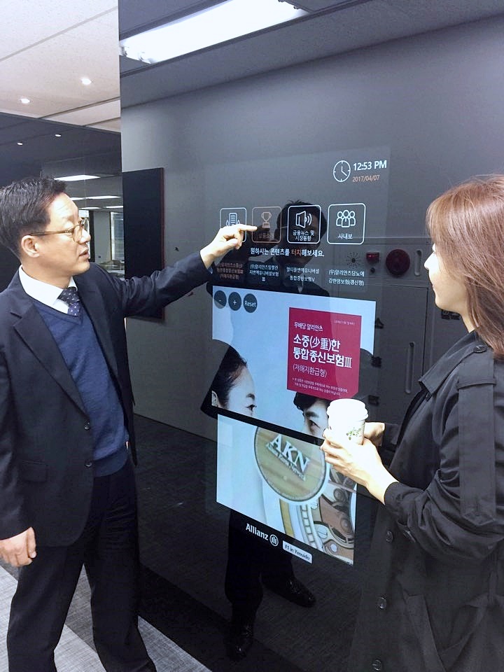 디지털 환경 영업점에서 직원들이 벽면에 설치된 디지털 기기 화면을 보면서 터치로 조작하고 있는 모습의 사진