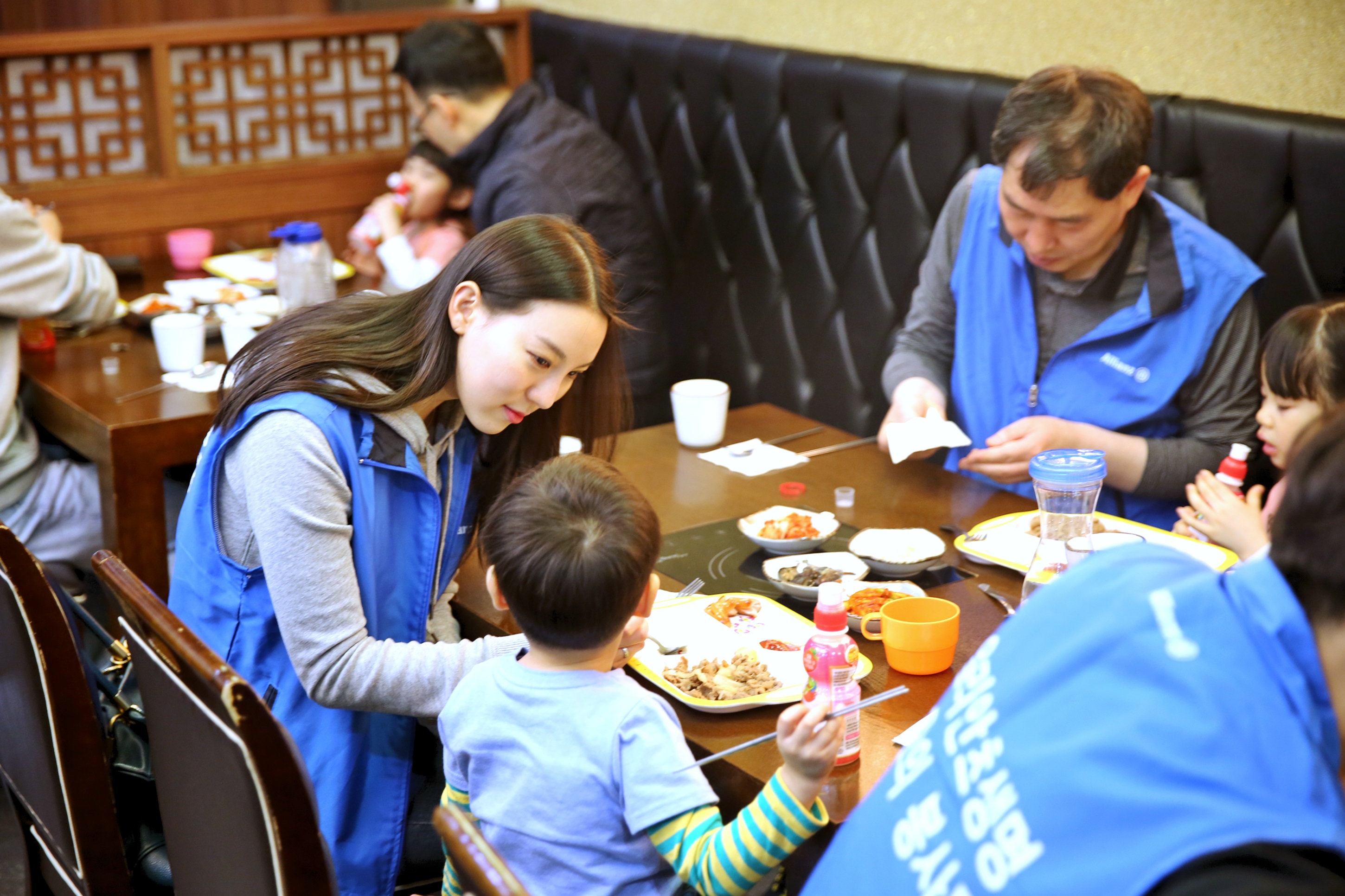 보육원 아이들과 놀이공원 나들이 중 직원들이 식당에서 아이들의 식사를 도와주고 있는 모습의 사진
