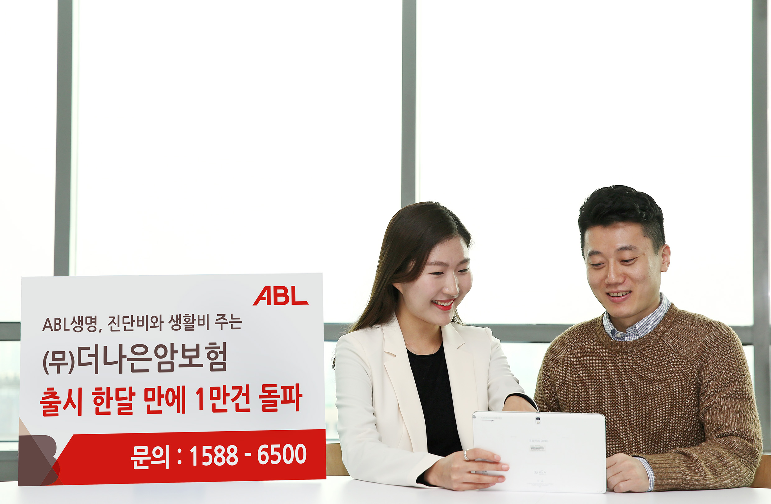 ABL생명, 진단비와 생활비 주는 (무)더나은암보험, 출시 한달 만에 1만건 돌파, 문의 : 1588-6500, 여성상담사가 밝게 웃으며 태블릿 PC로 남성고객에게 상품을 설명하고 있는 모습의 사진