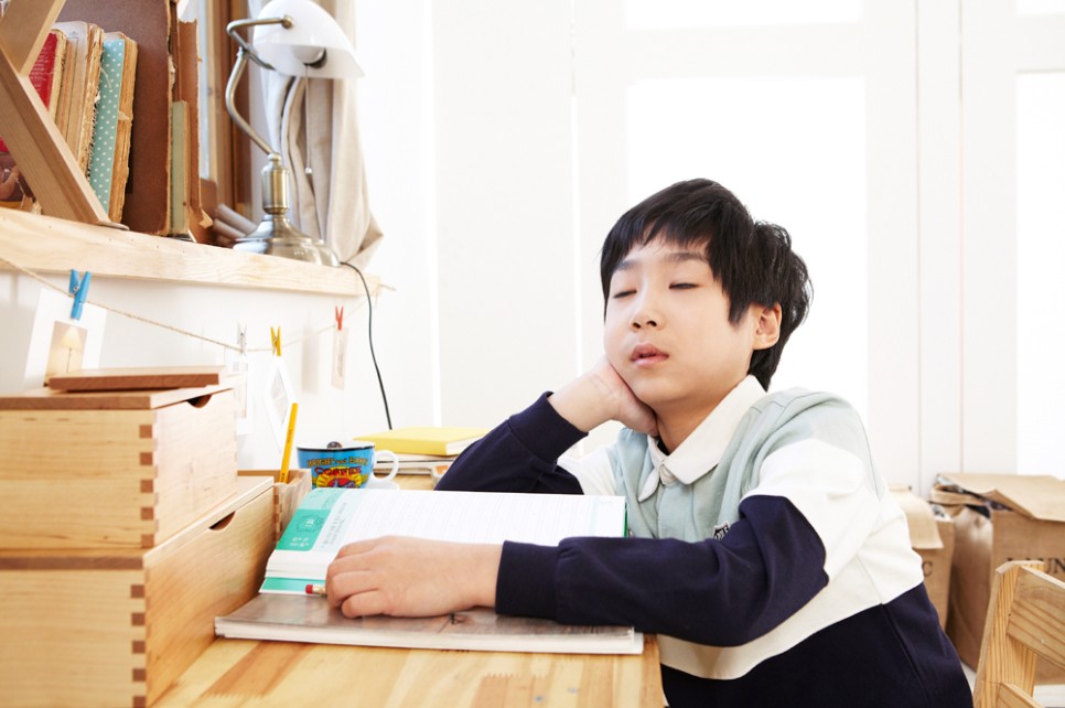 책상에 앉아 문제집을 펼쳐놓구 오른손으로 턱을 괴며 졸고있는 아이 사진