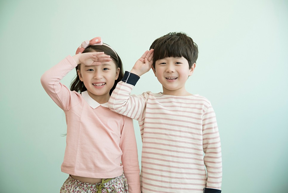 경례 자세를 하며 활짝 웃고있는 여자아이와 남자 아이